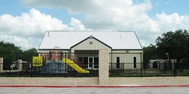 Fenced playground with yellow slide and building